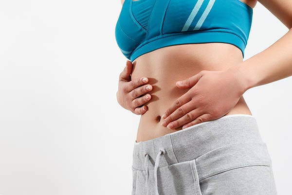 Woman holding her stomach, reflecting on women's digestive and nutritional health