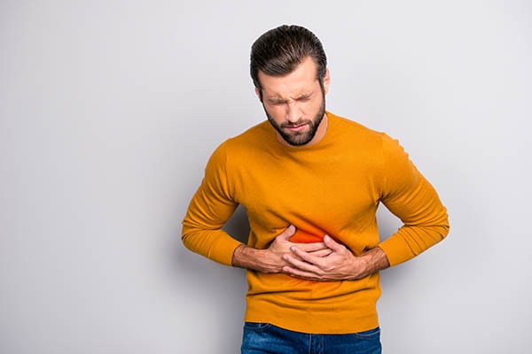 Man holding his stomach in discomfort from a digestive disorder